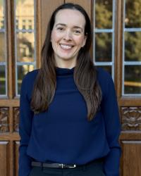 an image a woman in a blue blouse standing in front of a wooden door 