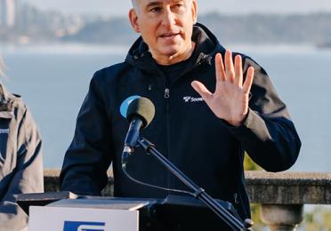 Dow Constantine speaking outside with microphone, with Sound Transit logo visible.